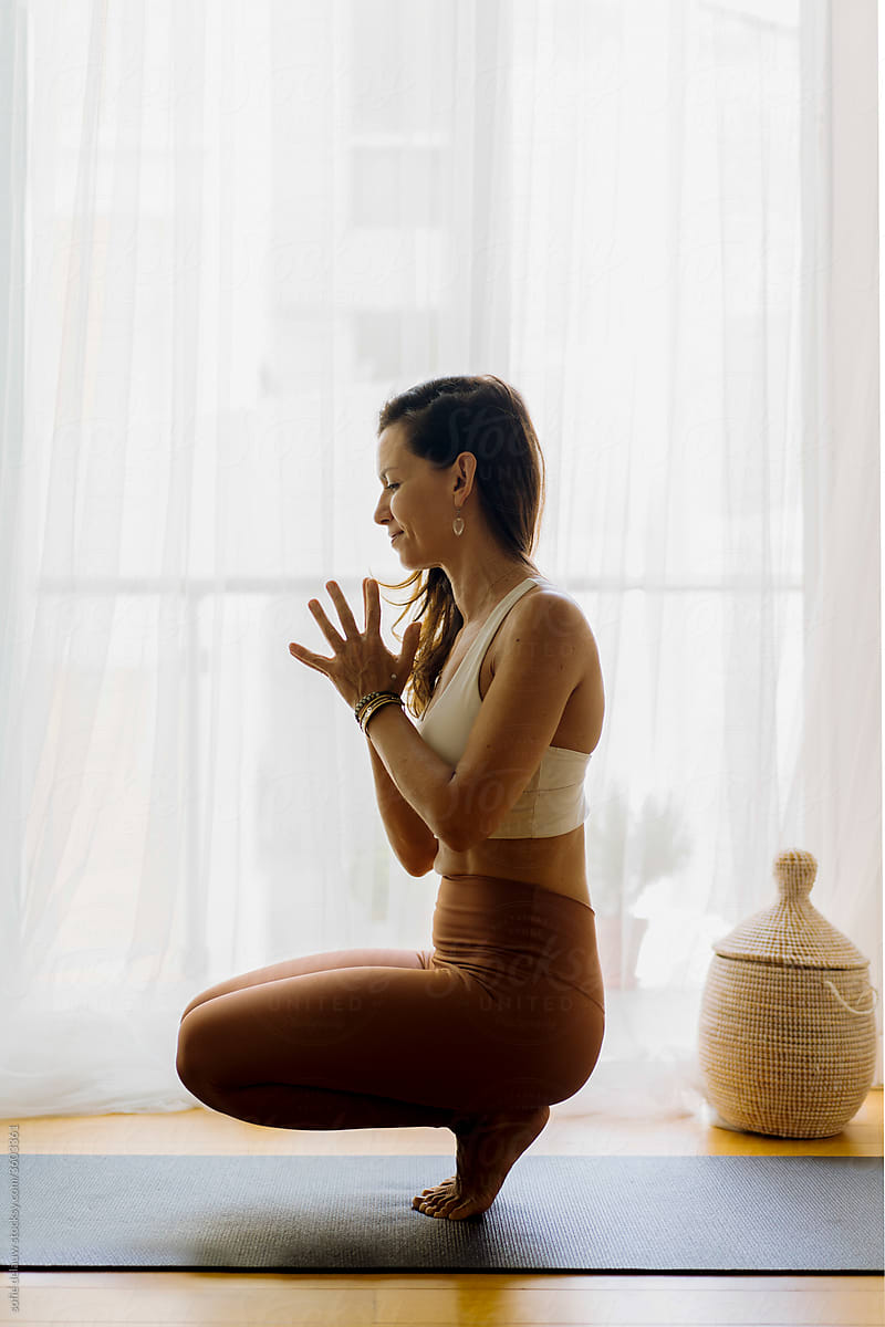 Concentrated woman doing balancing yoga asana