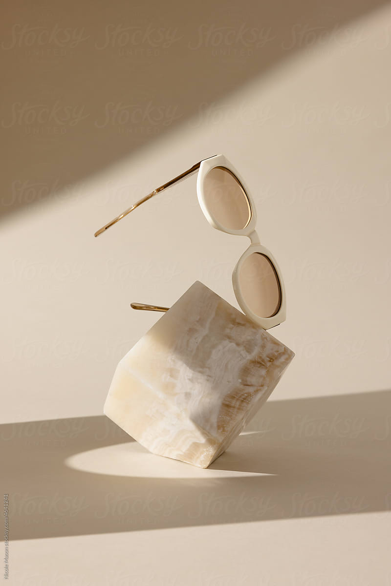 sunglasses floating over beige marble cube