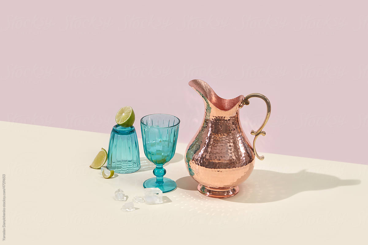 Shiny copper jug and blue glass with lime drink.