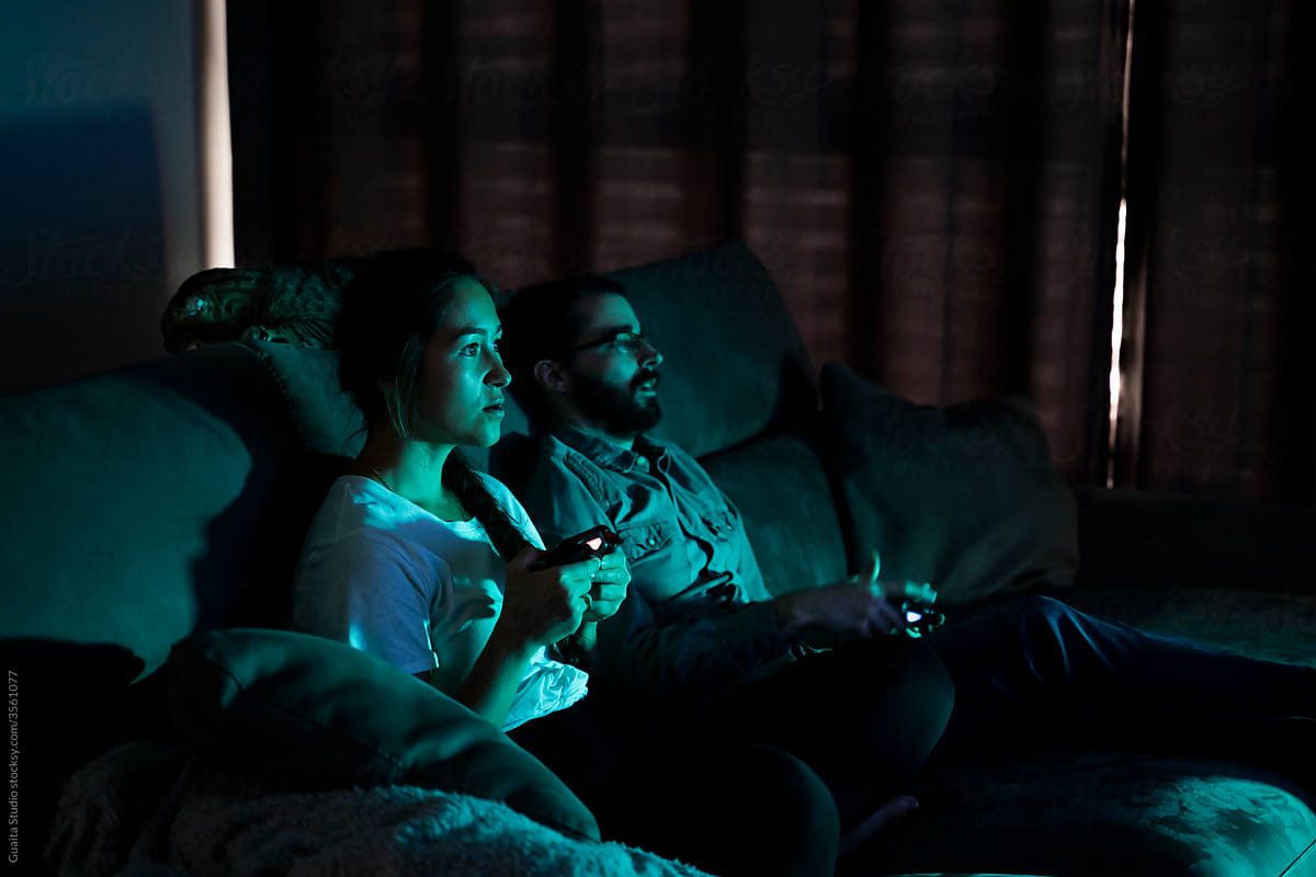 Focused couple playing videogames at night