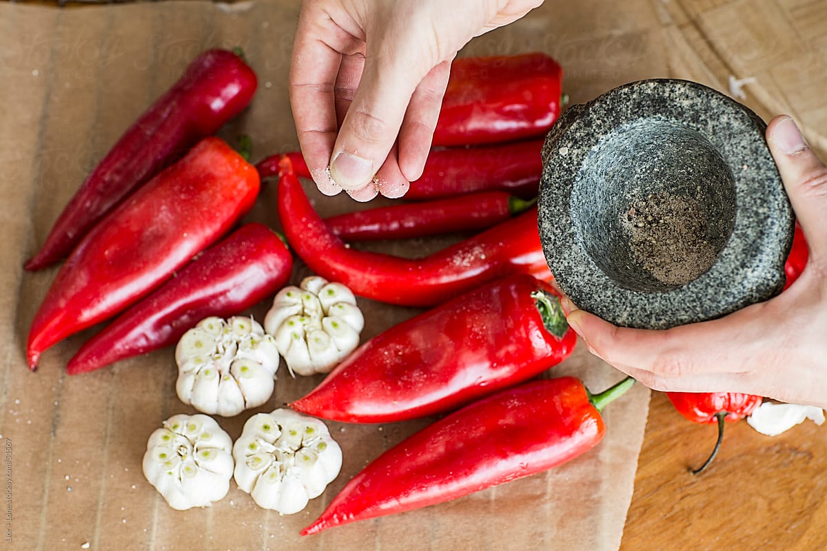 Hand holding mortar pouring black pepper on vegetables