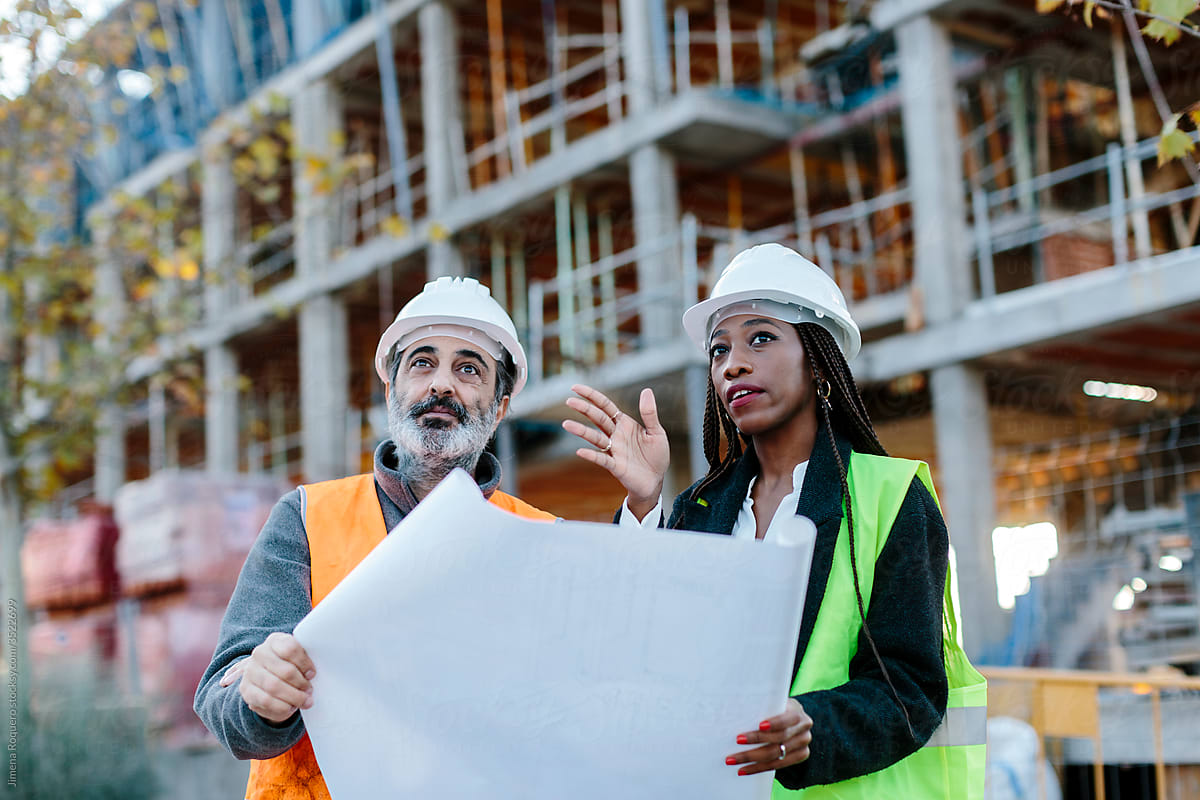 Woman engineer giving instructions to  construction worker based on blueprints.