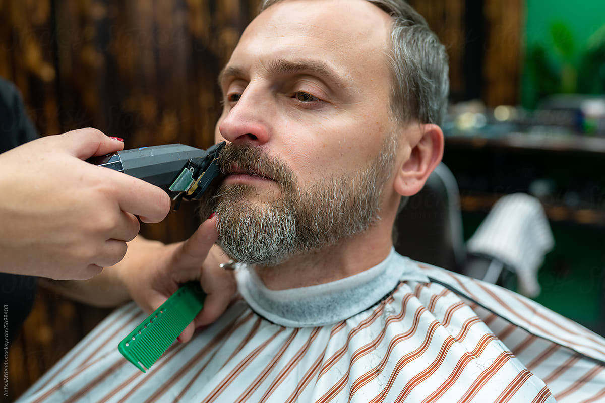 man having his beard cut by electric shaver