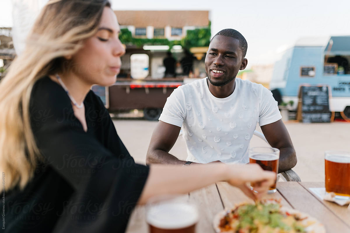Black man and Spanish woman having lunch in the street