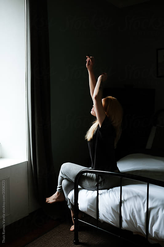 woman stretching her arms while is sitting in the bed in the mourning