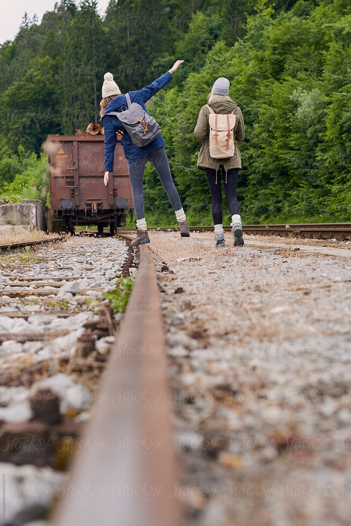 Adventure girl friends balancing on train rail tracks having fun