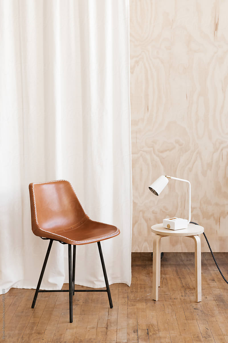 leather chair and modern white lamp in modern studio with plywood backdrop