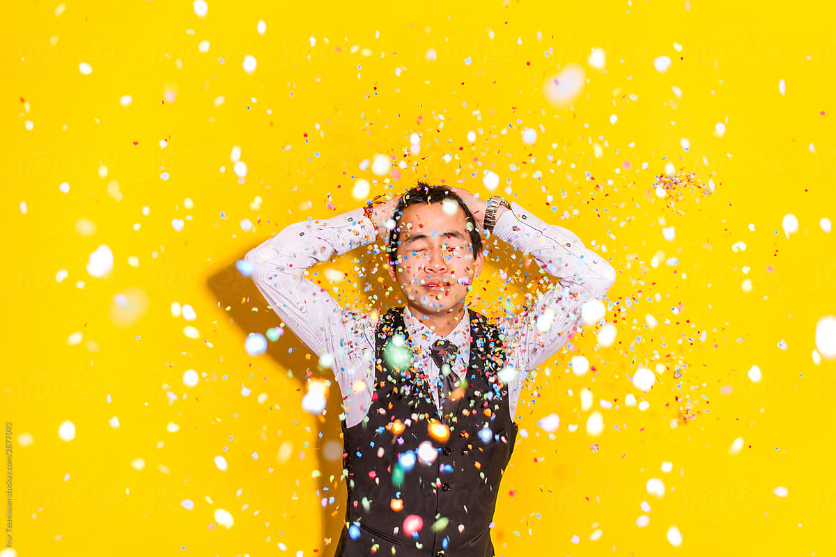 Asian Man with hands behind his back surrounded by confetti