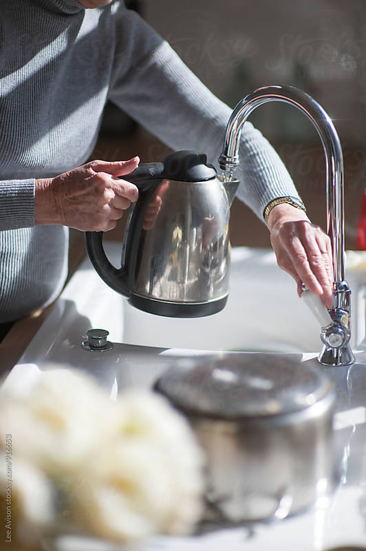 senior woman filling a kettle with water