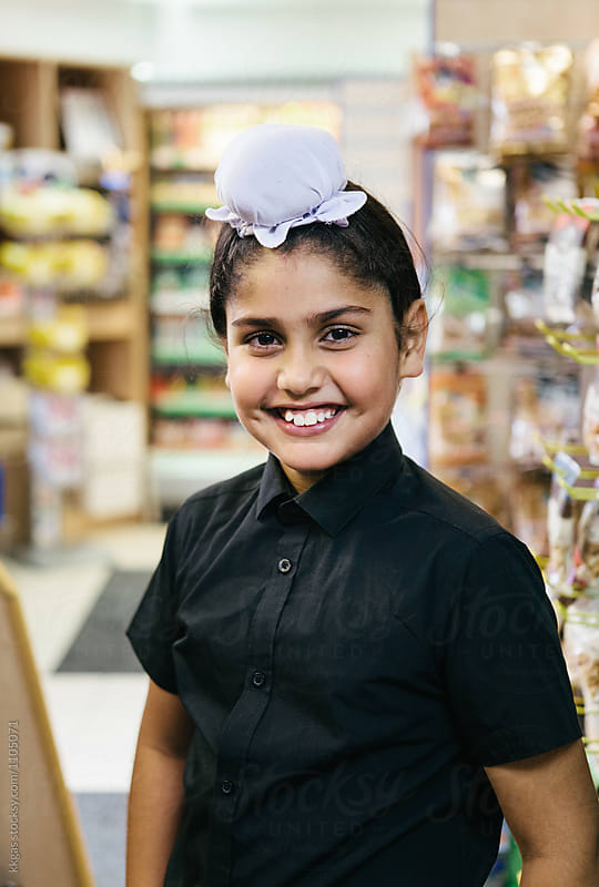 Happy young Sikh indian boy wearing a rumal inside a shop