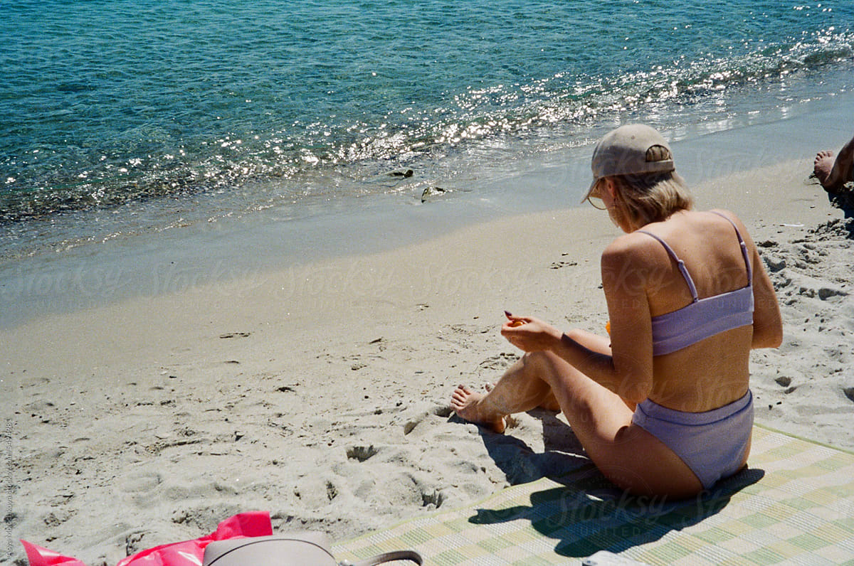 Woman sunbathing at the beach and using spf cream