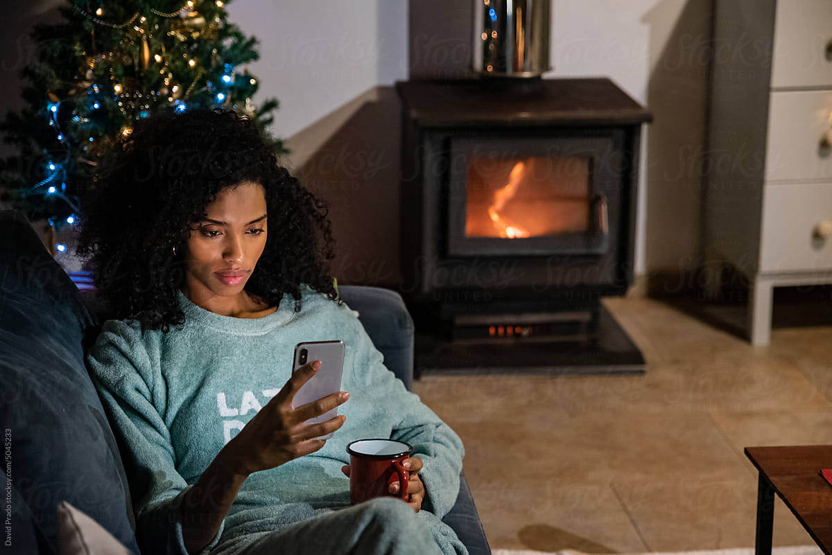 Black woman using smartphone on sofa