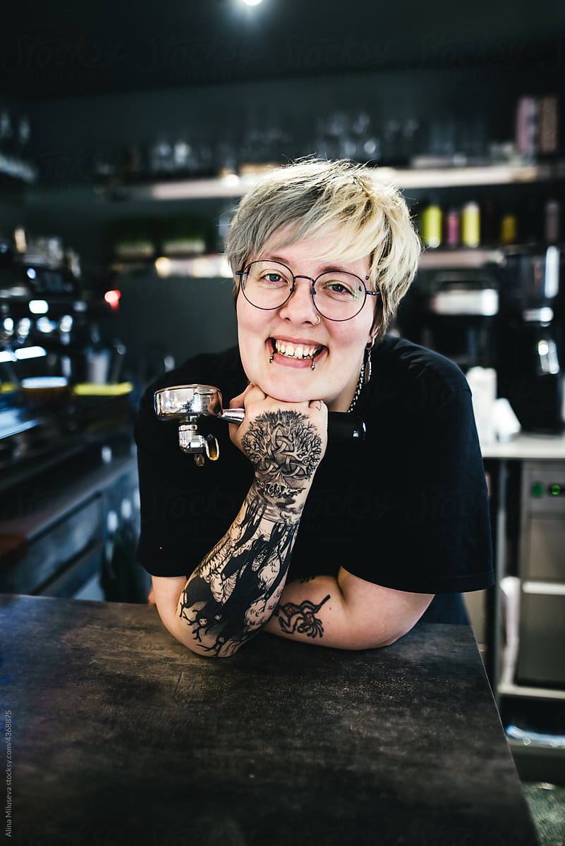 Smiling tattooed woman barista in cafe