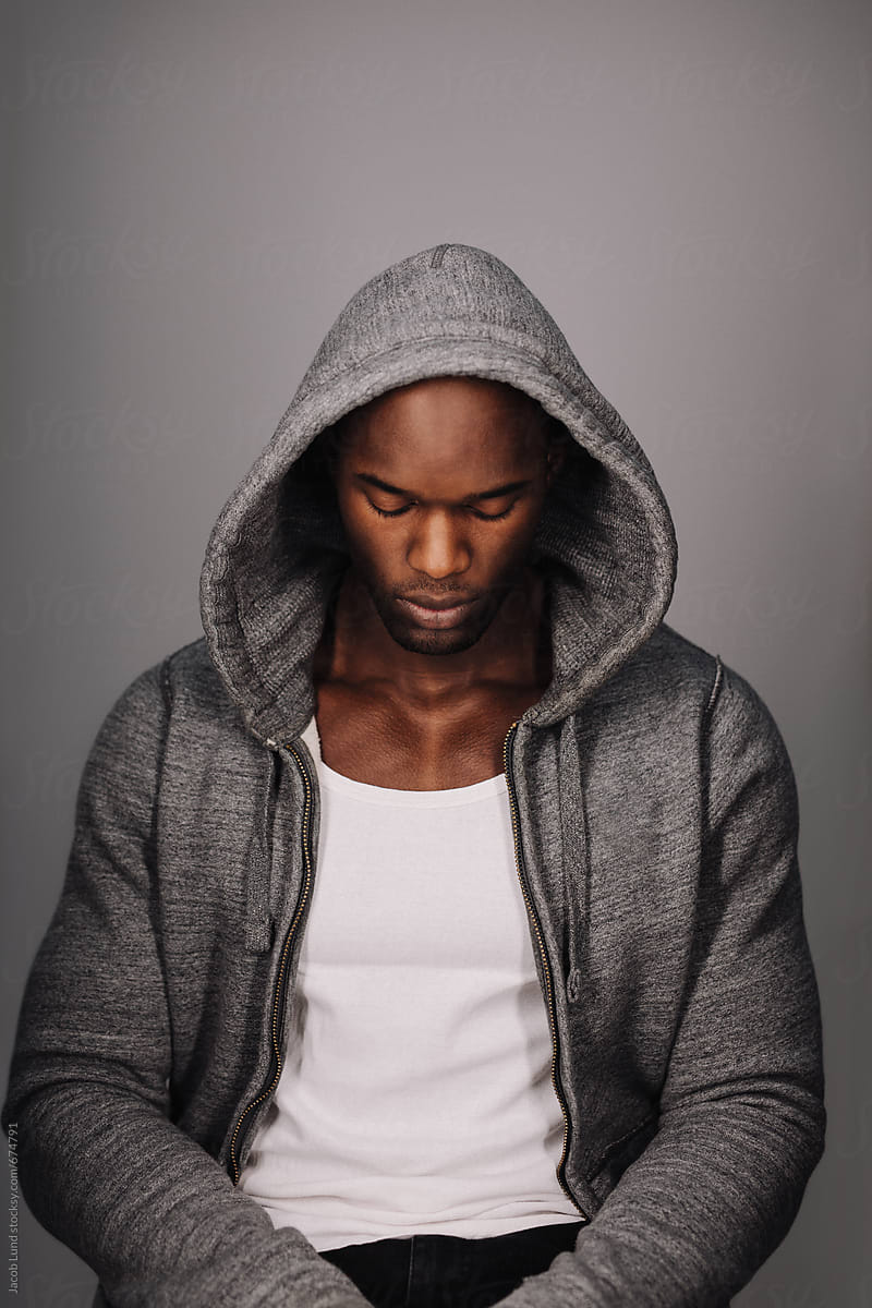 Calm young man in a hoodie looking down