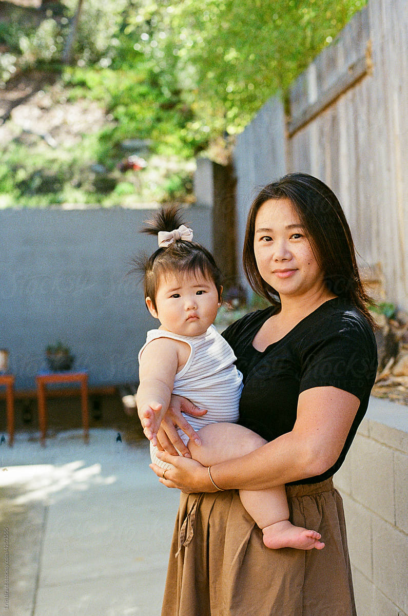Asian mom holding chunky baby outside