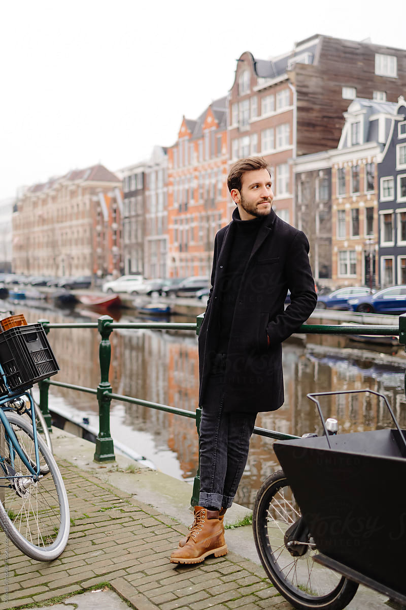 Male model standing on walkway beside of Amsterdam canal