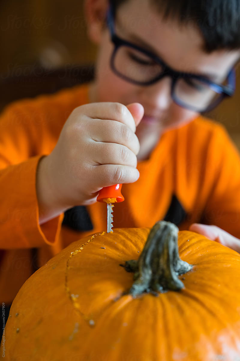 Boy cutting pumpkin for Halloween celebration