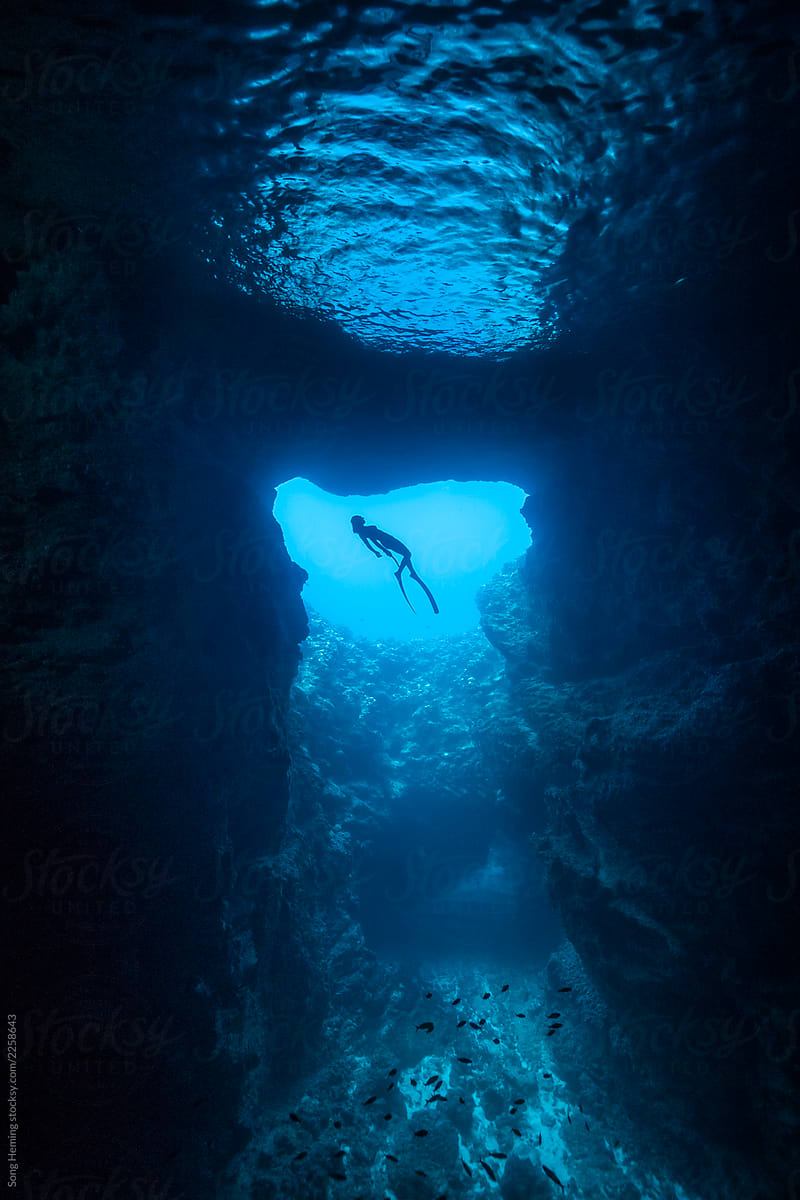 Female free diver underwater in the cavern with back light