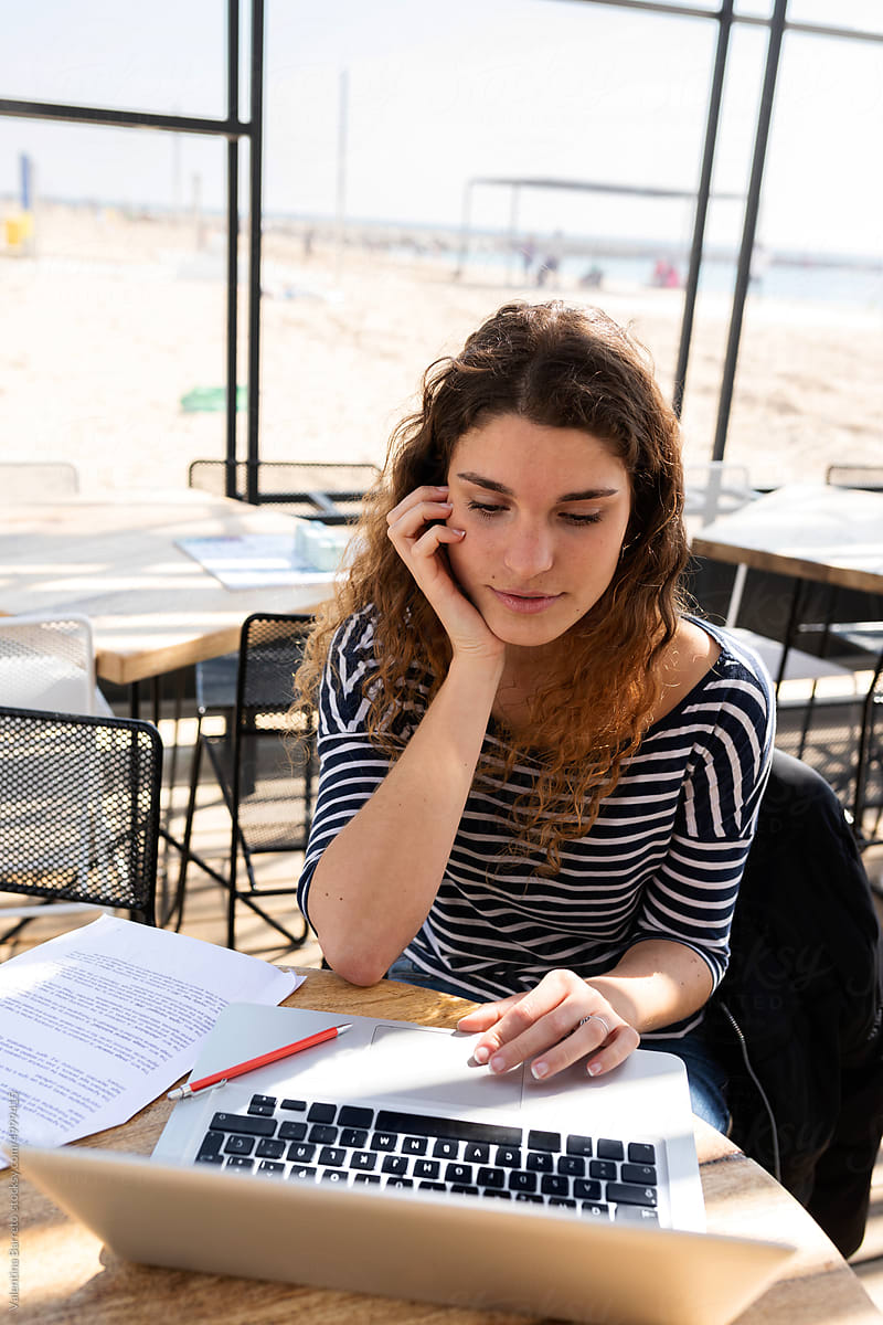 Young woman studying for an exam at beach bar