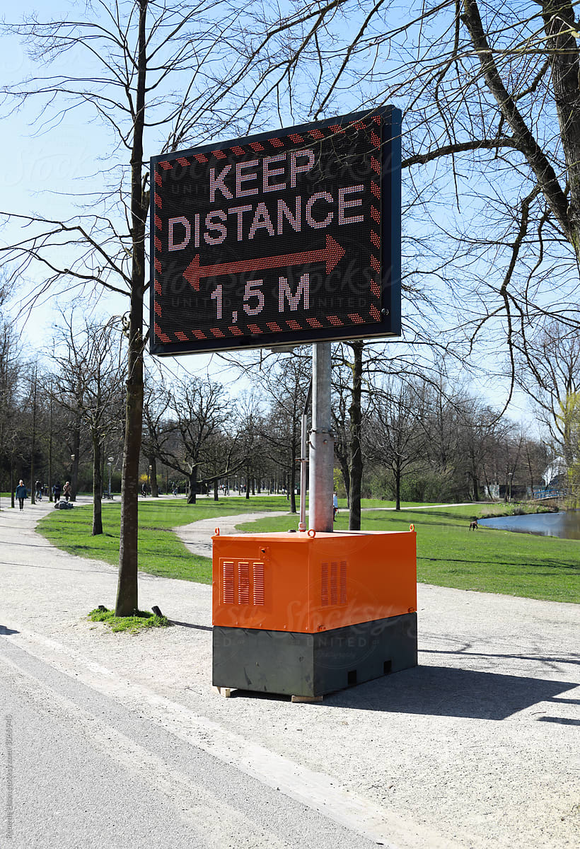 sign in park with warning to keep distance
