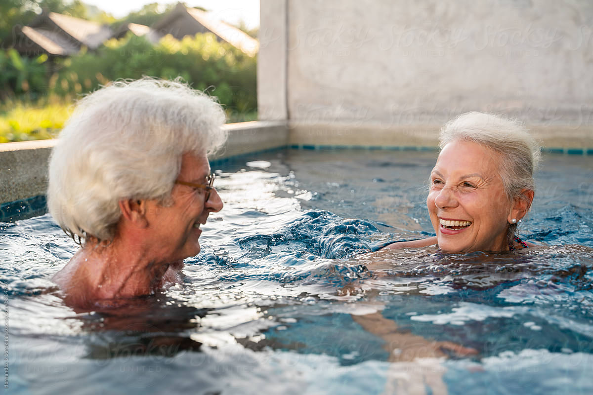 Cheerful Senior Couple Swimming Together In The Pool