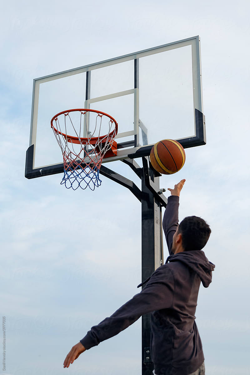 Anonymous basketball player jumping and throwing ball into ring