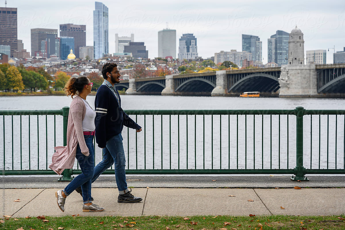 African American Couple Walking in step  on Riverfront  with Boston Skyline