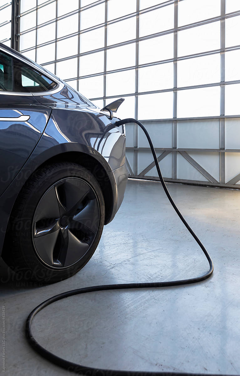 Electric car charging with cord in modern garage