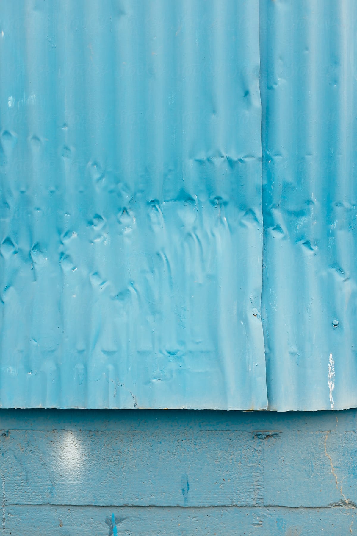 Painted blue metal siding of warehouse exterior, close up