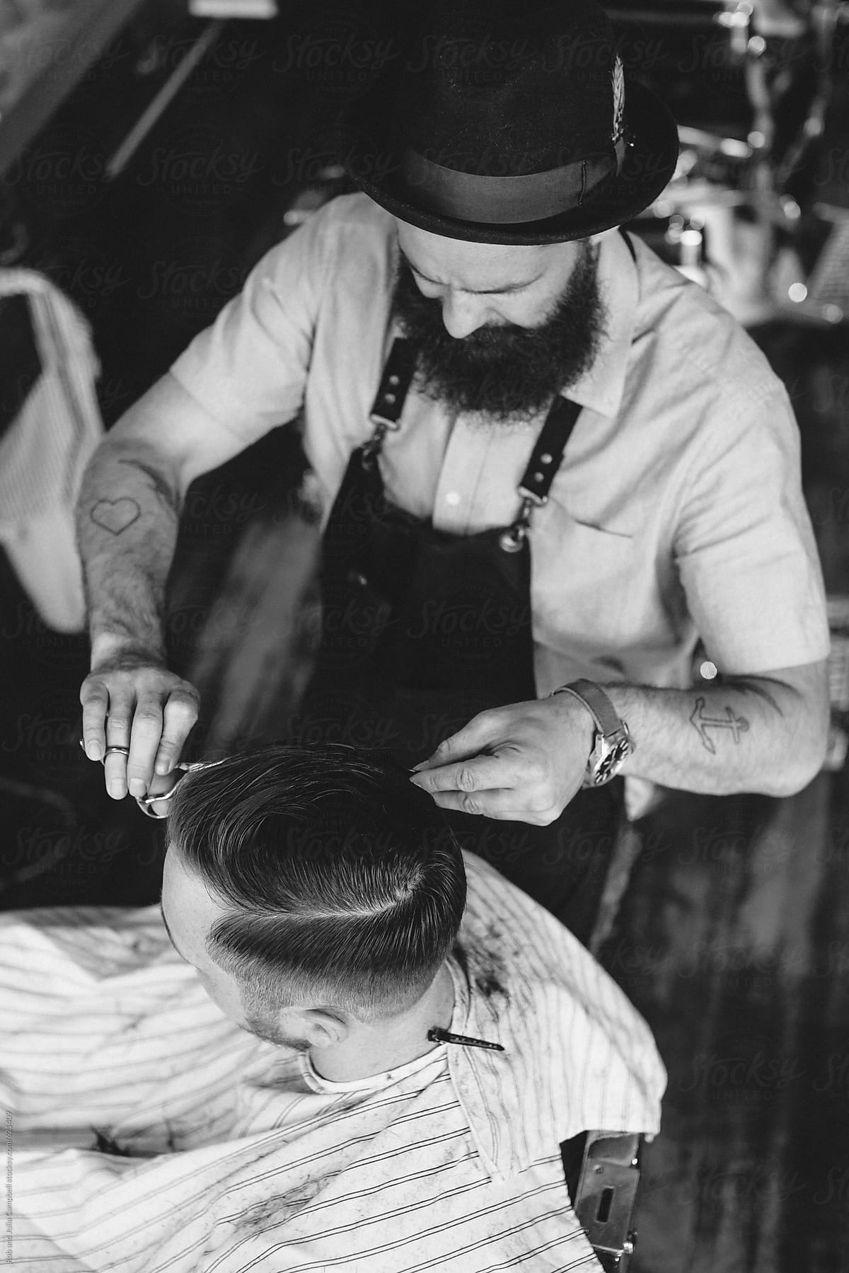 Stylish modern barber giving man a classic haircut - top view