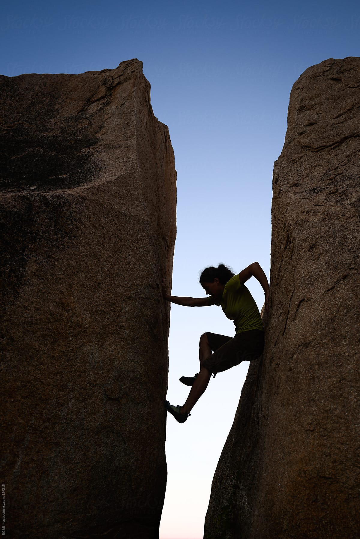 Woman silhouette climbing between two rock walls