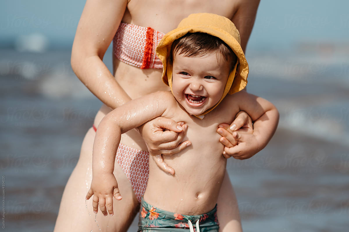 Wet kid with mother on beach