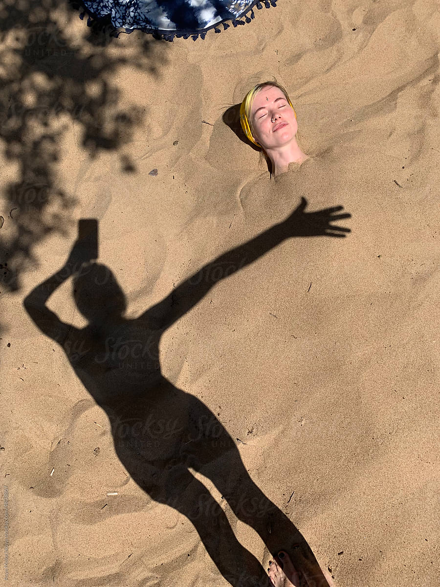 Woman lying under the sand on the beach