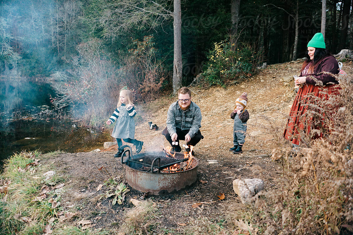 family making smores  by a camp fire by a lake