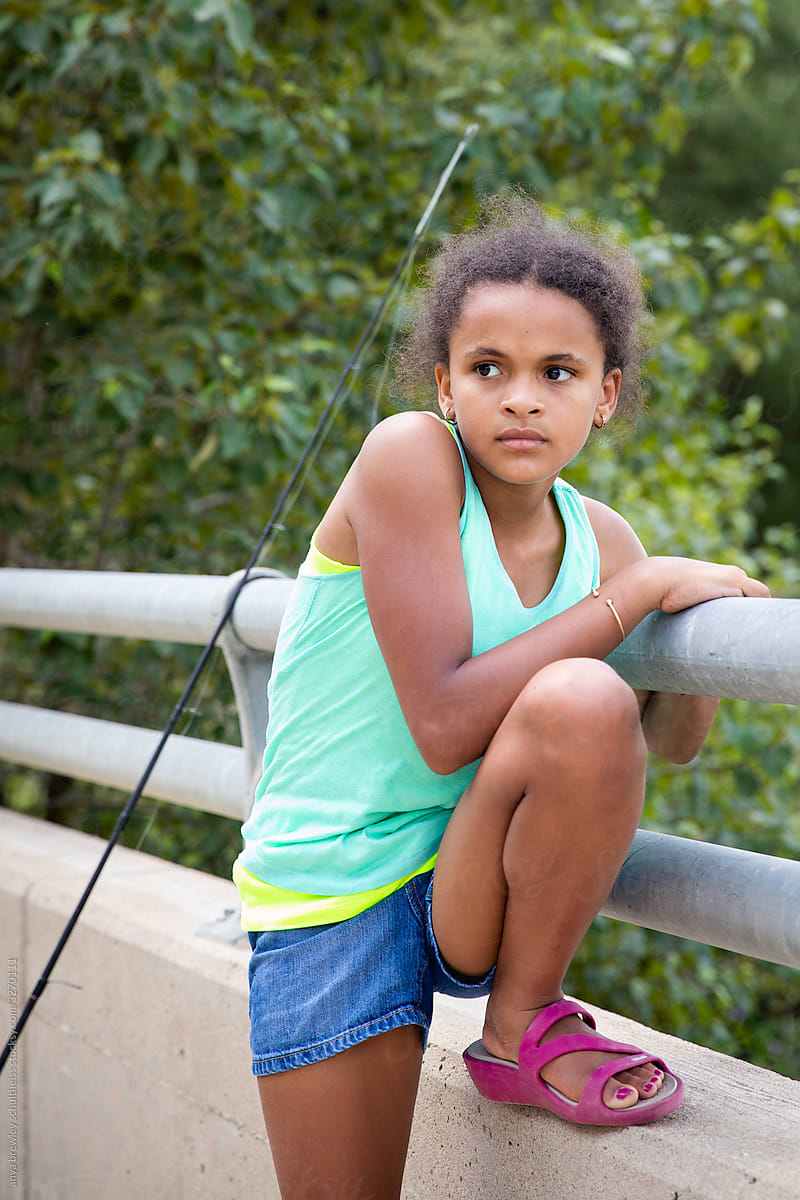 Girl leaning against the metal rail of a bridge.