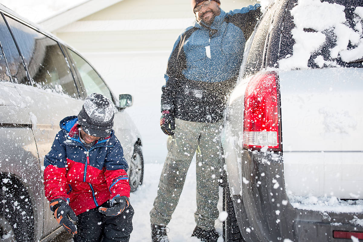father and son clean snow off suv