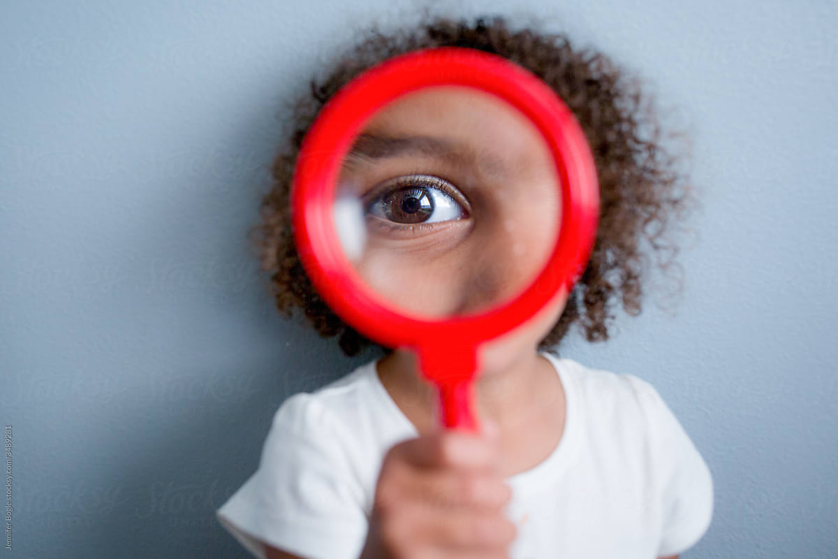 Girl looks through red magnifying glass