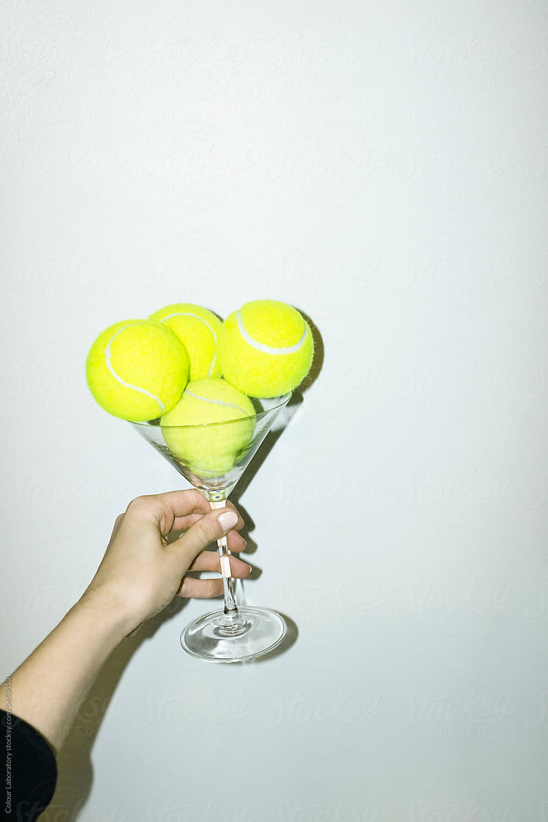 Neon green tennis balls in martini cocktail glass and hard flashlight