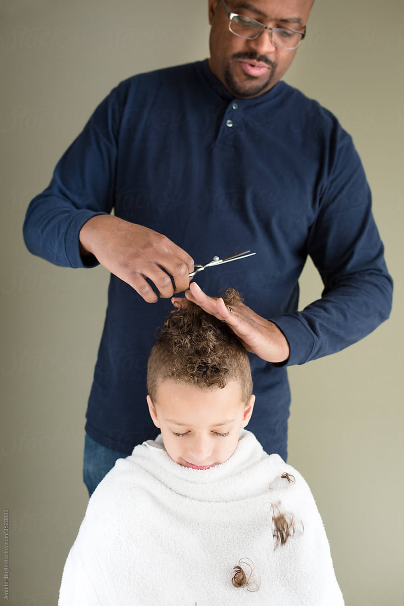 Curls fall as father trims son\'s hair