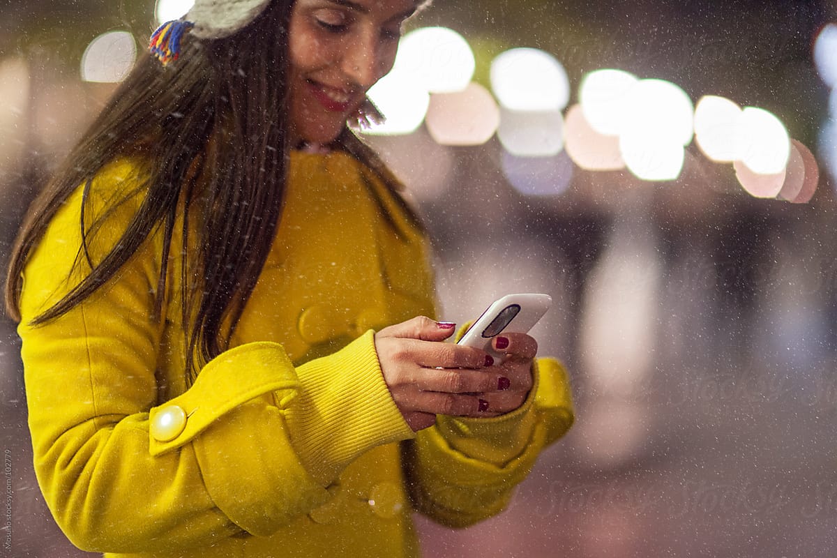 Woman Typing on Her Phone on a Snowy Night