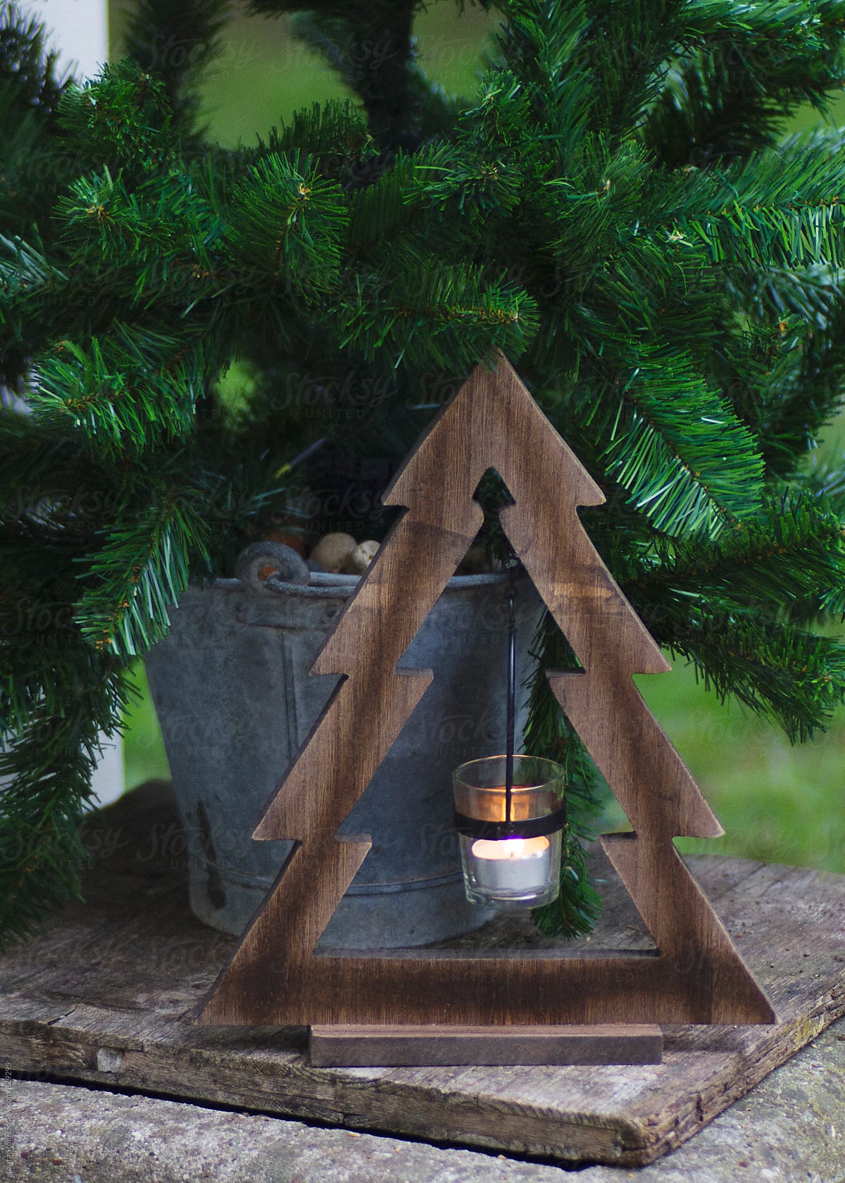Christmas tree shaped wooden candle holder close to spruce tree in garden