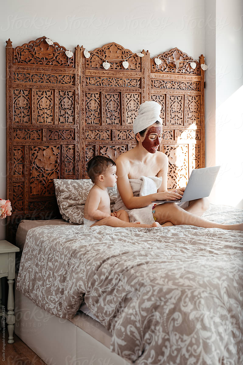 Beautiful mom with son using laptop on bed.