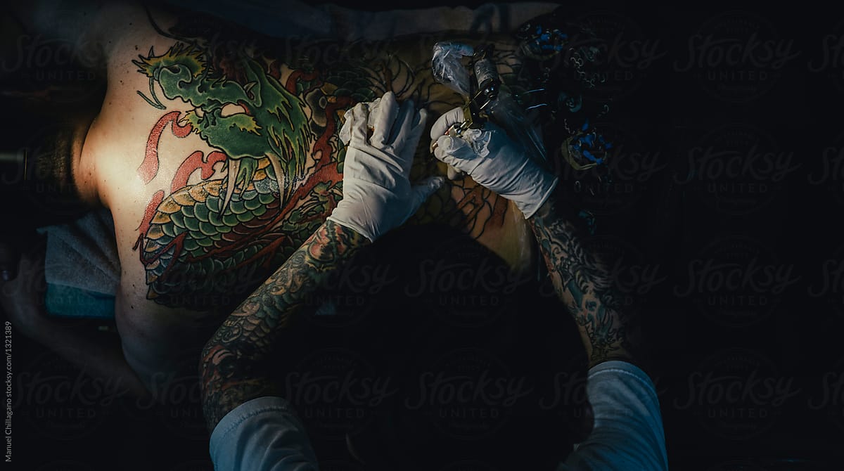 Japanese tattoo artist is tattooing the back of a client