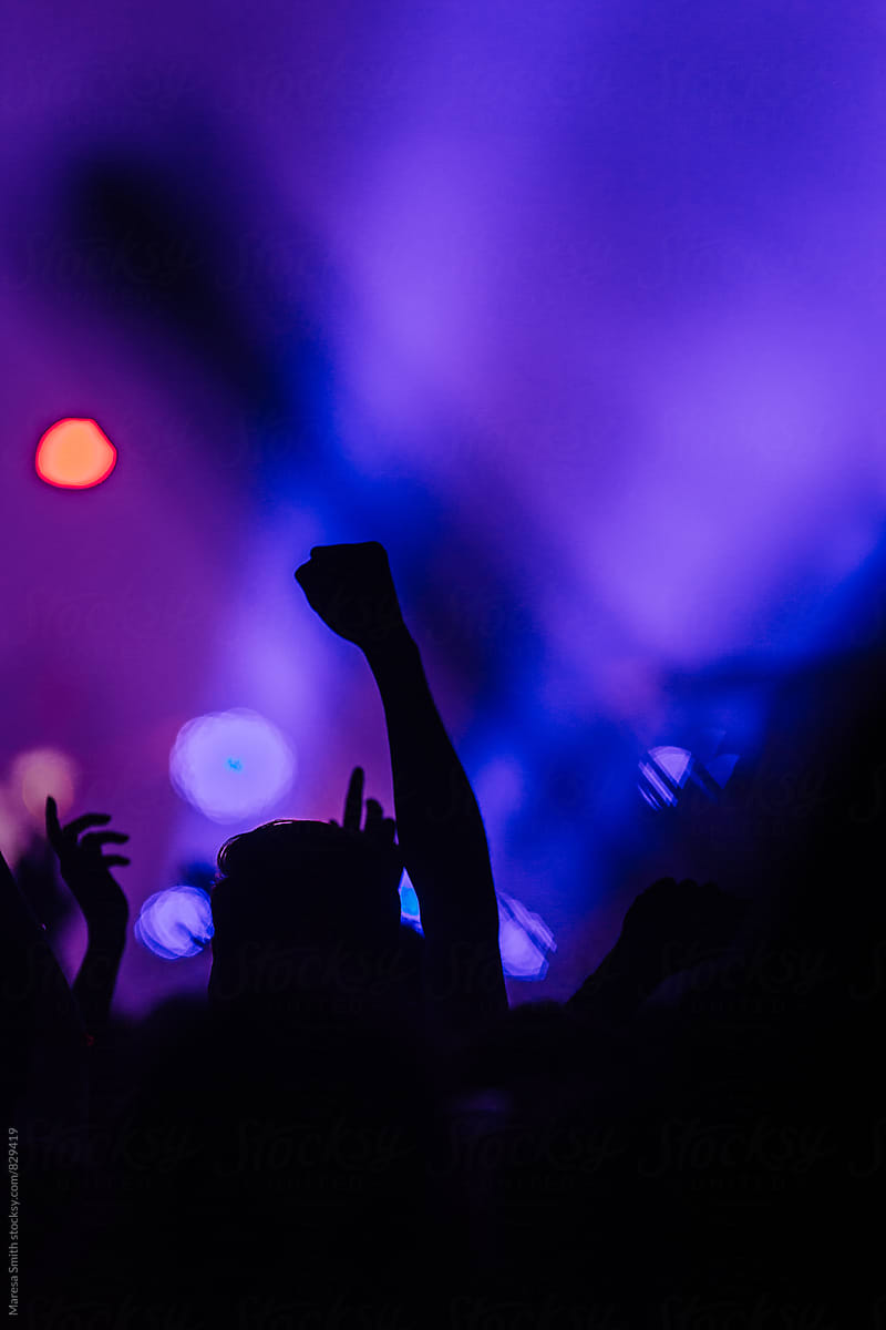 Silhouetted fist in the air at a colourful concert