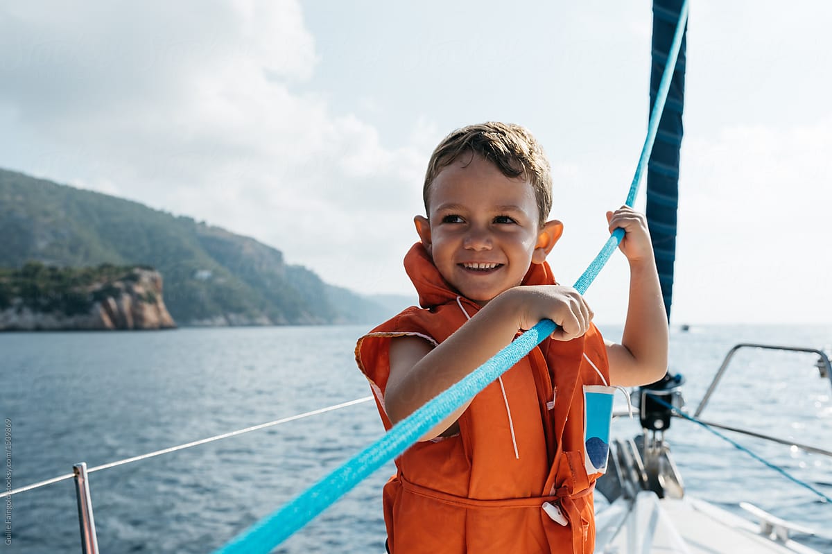 Happy boy holding rope on boat.