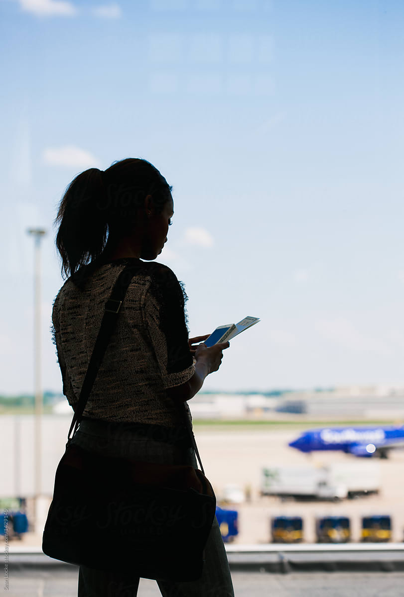 Airport: Silhouette Of Female Traveller Standing By Window