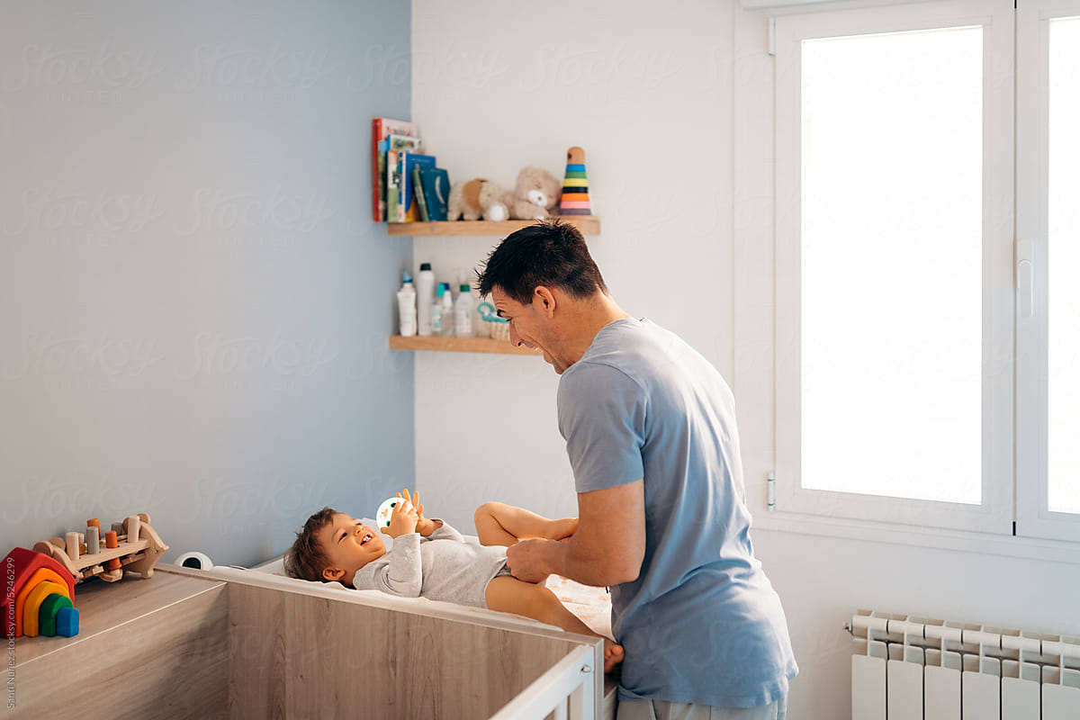 Father playing with his son on the nappy changing table