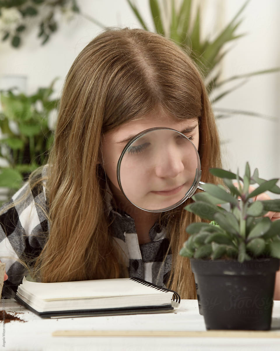 Student Looking Through Magnifying Glass at Plant