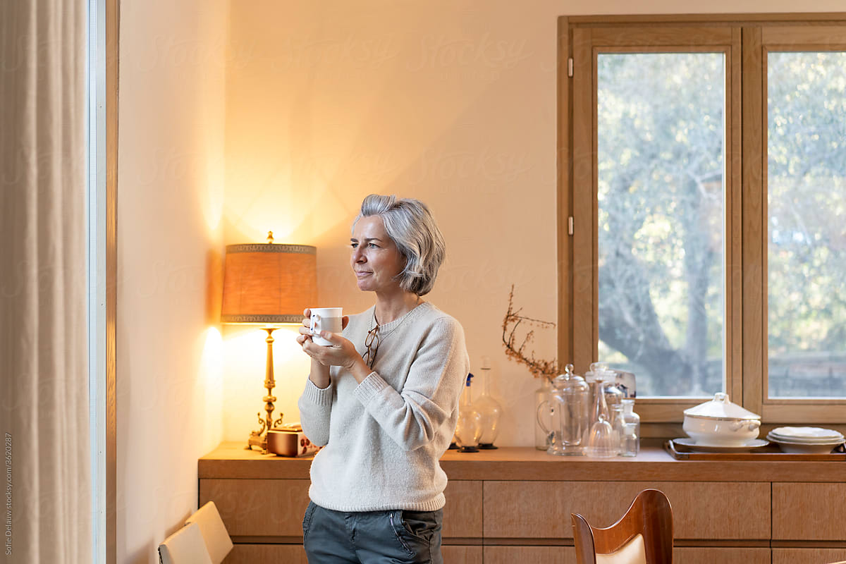 Middle aged woman enjoying hot drink in cozy room