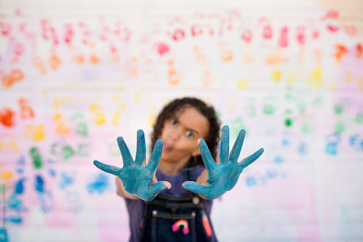 Out of focus girl holds out blue painted hands